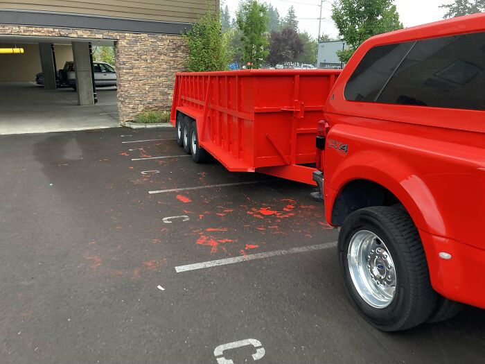 Red truck parked poorly across multiple spaces, capturing online frustration.