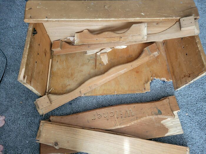 Broken drawer pieces on a grey carpet, showing damage and frustration in an online post.