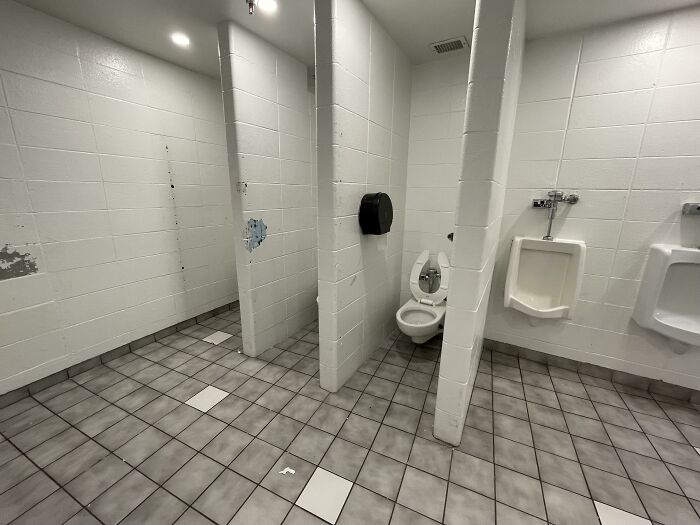 Public restroom with a poorly constructed toilet area, highlighting frustrating design choices.