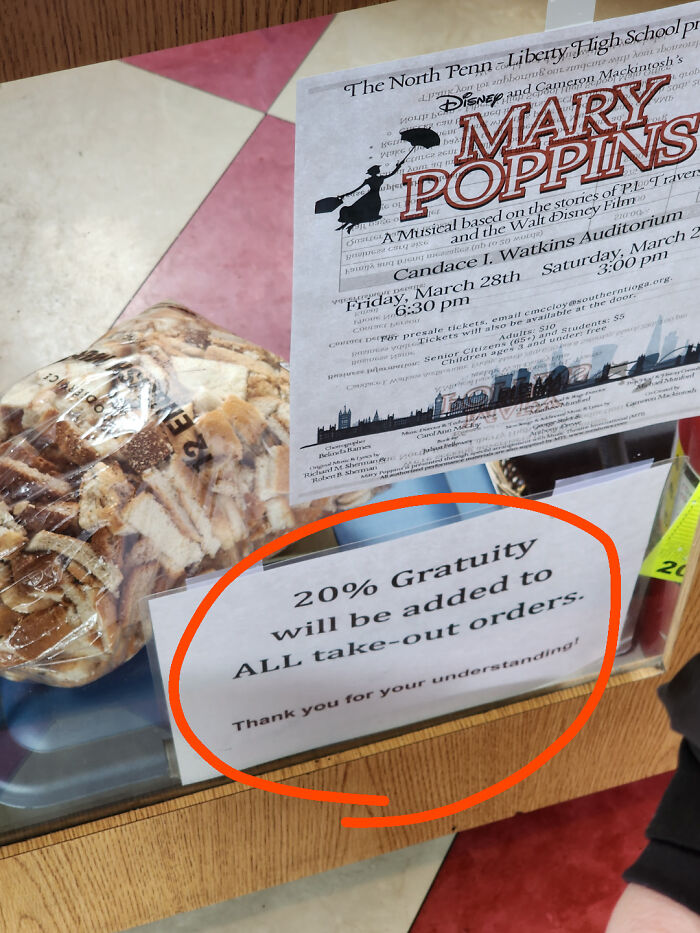 Sign announcing a 20% gratuity on all take-out orders near a Mary Poppins poster.