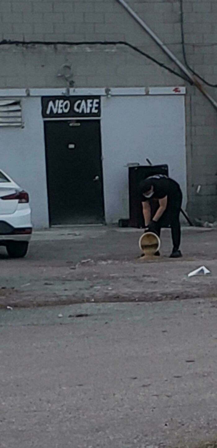 Person pouring liquid outside Neo Cafe, expressing frustration.