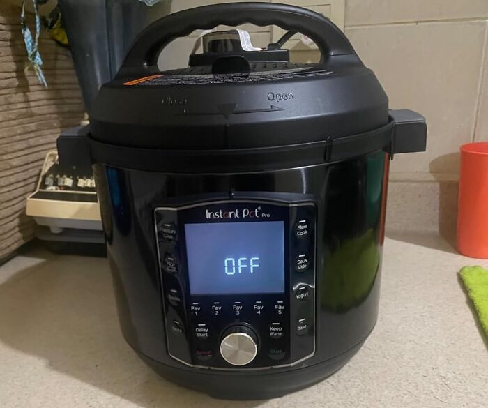Instant pot on counter, essential for those living the solo life, screen displays "OFF" with kitchen items in the background.