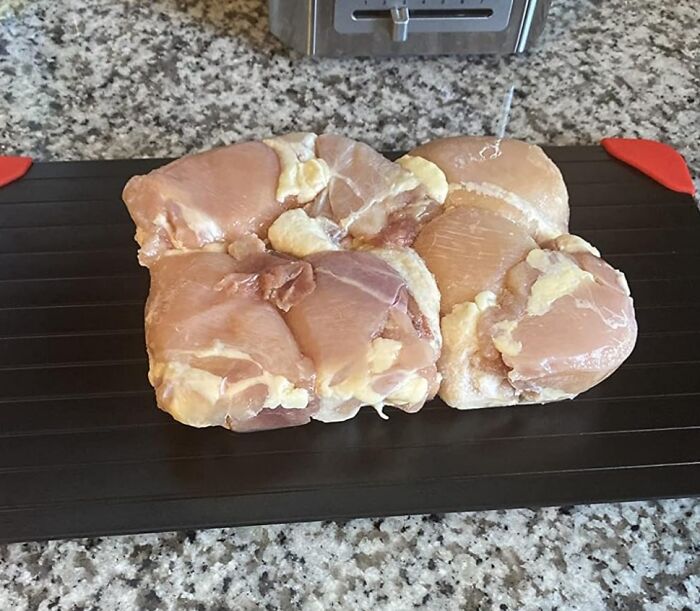 Frozen chicken thawing on a countertop on a defrosting tray, essential for solo living convenience.