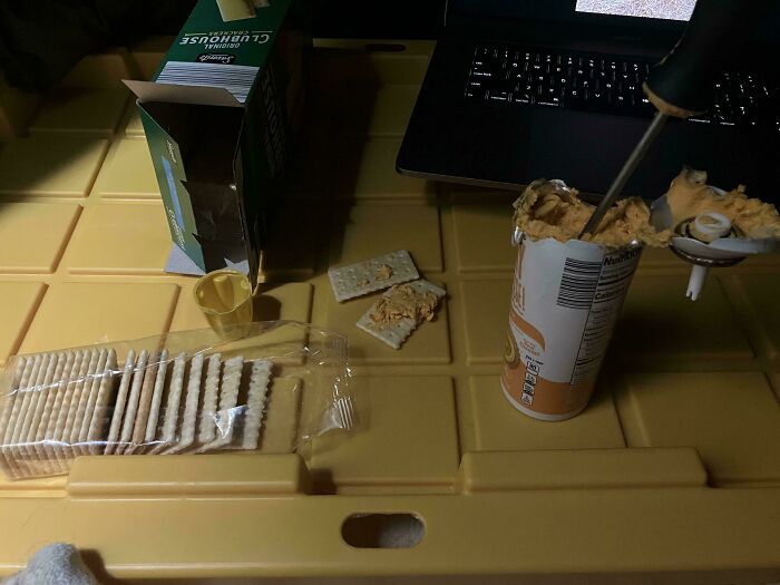 DIY snack hack: crackers and cheese taken from a can using a tool on a yellow table.
