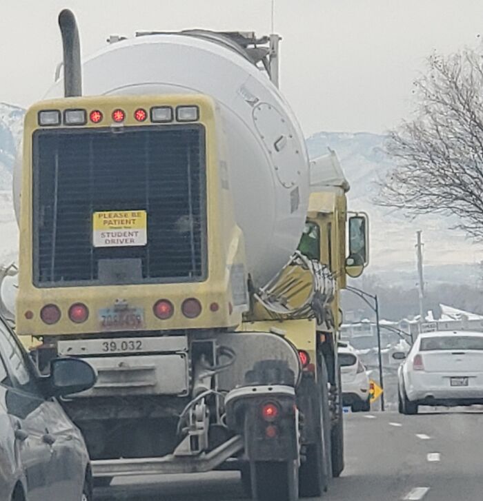 Unusual cement truck with "Student Driver" sign looks fake but is real, driving down a snowy road.