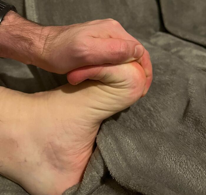 Hand gripping a foot, creating an illusion that appears fake upon first glance but is actually real.