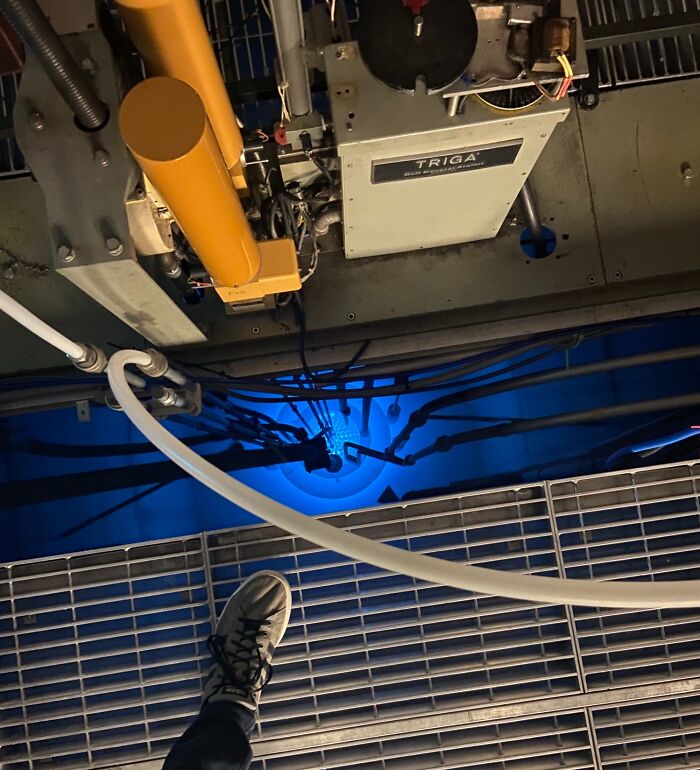 A mechanical room with a glowing blue light and foot on a metal grate, appearing surreal but real.