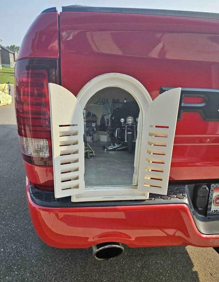 Red truck with window illusion on the tailgate showing a garage scene, a photo that looks fake but is real.