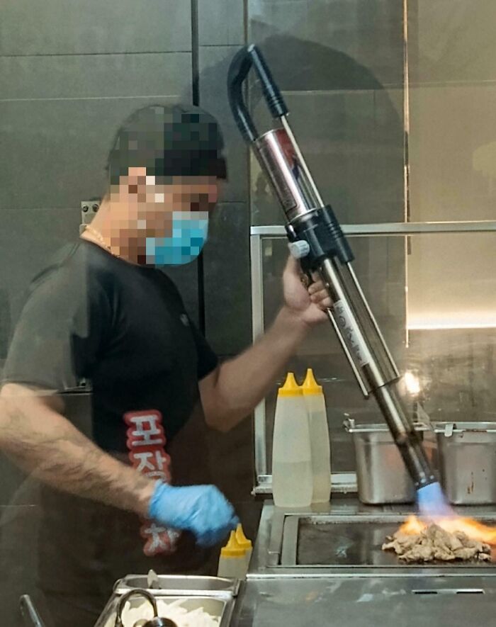 A chef using a flamethrower for cooking, demonstrating a unique but real kitchen technique.