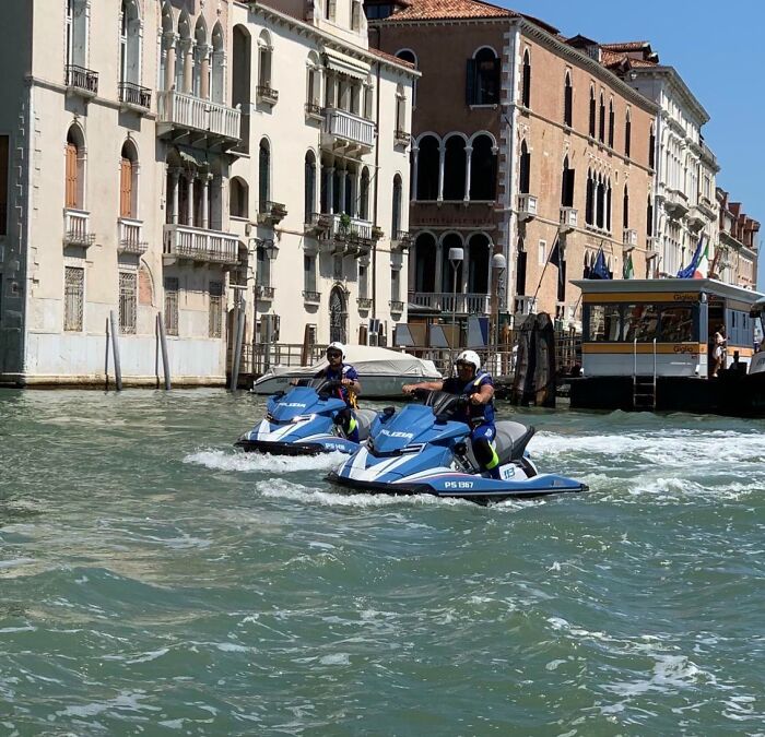 Police officers on jet skis patrolling canals in Venice, showcasing a scene that looks fake but is real.