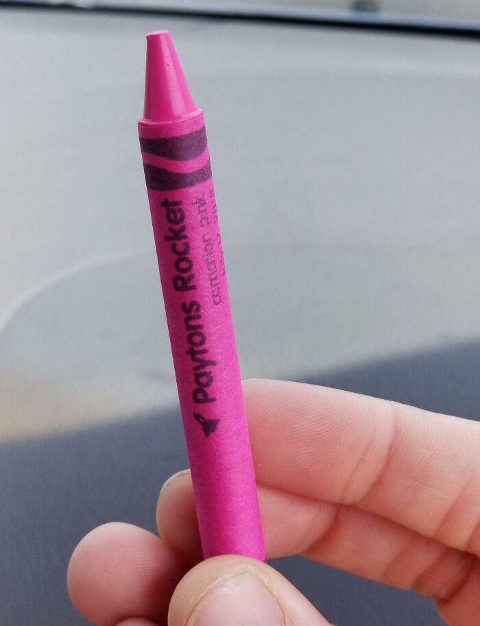 A man humorously holds a bright pink crayon labeled "Paytons Rocket," showcasing his playful side.