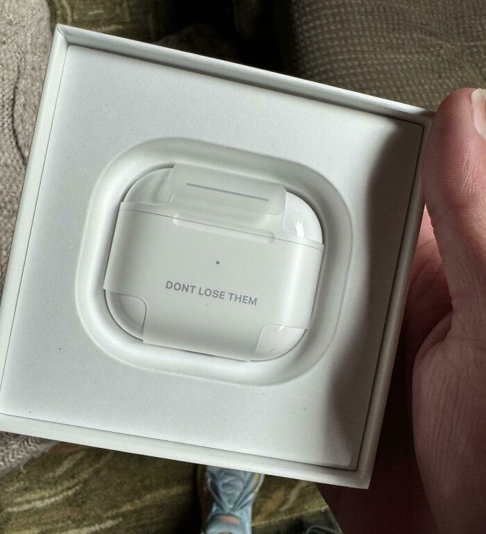 White earbuds case with "DON'T LOSE THEM" text, showcasing a humorous reminder.