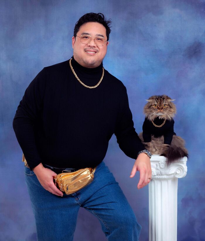Man with a gold waist bag and his cat, both in black outfits, posing humorously against a purple backdrop.