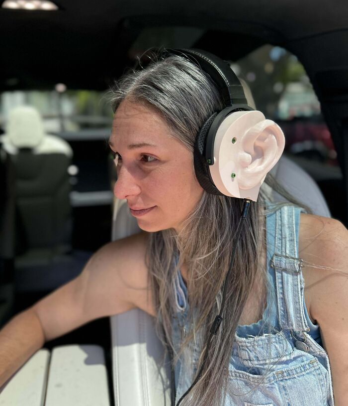 A woman wearing headphones with large ear designs, creating a humorous appearance.