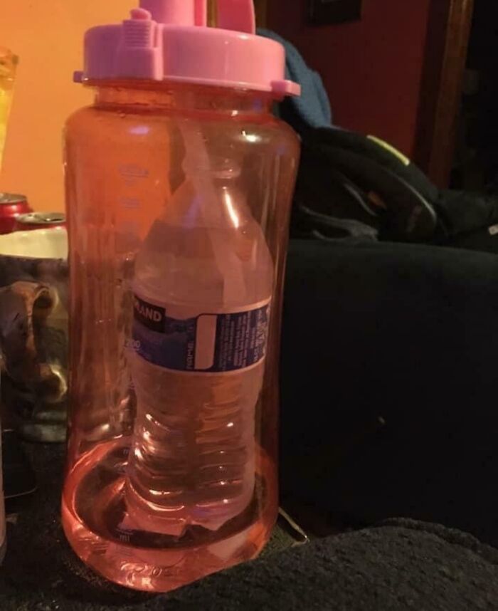 A water bottle humorously placed inside a larger pink jug, showcasing funny men and their quirky antics.