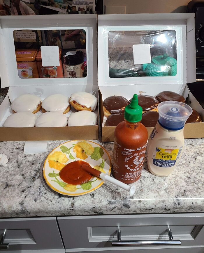 Funny coworkers set up donuts on a counter with hot sauce and mayo for a humorous prank.