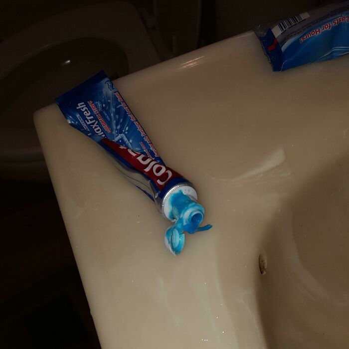 Toothpaste tube improperly squeezed on a sink, highlighting poor etiquette.