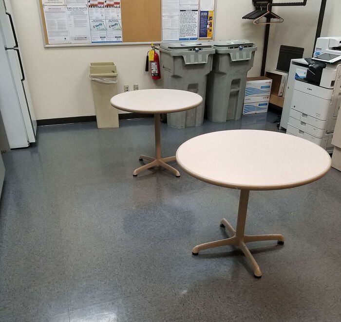 Break room with two small tables, recycling bins, and a copier showcasing infuriating superiors' choices.