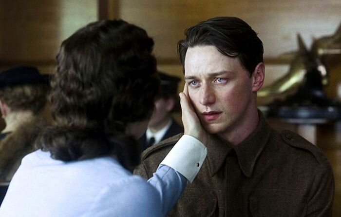 Man in military uniform with teary eyes, touched gently by a woman, evoking emotion and tears in a heartfelt scene.
