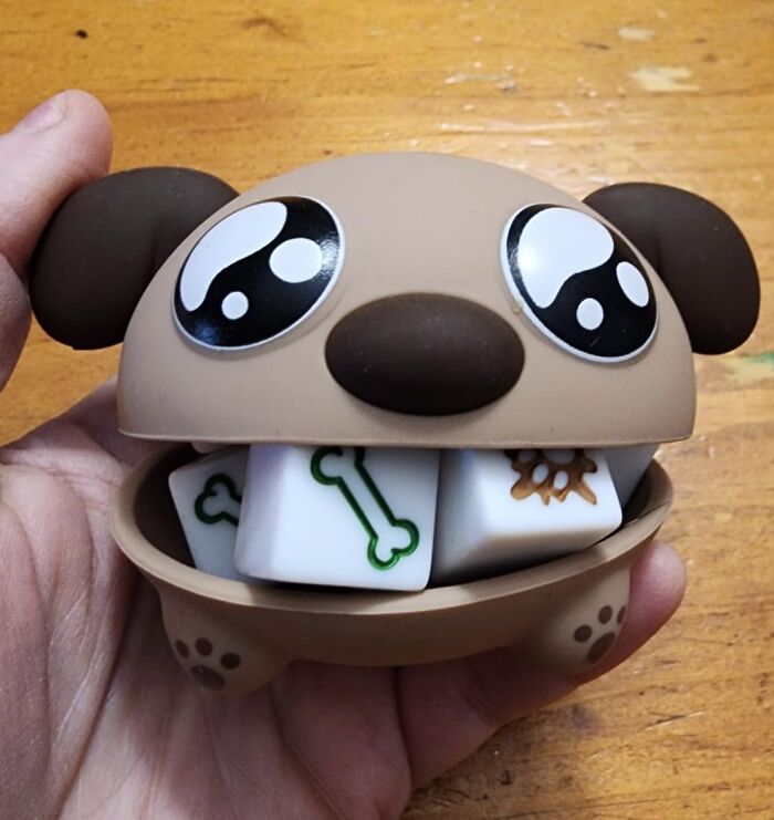 Quirky dog-themed dice holder with cartoon eyes and bone-decorated dice, perfect for the weird friend.