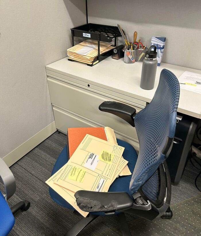 Worn office chair with damaged armrest, cluttered desk surface in a workspace of infuriating bosses.