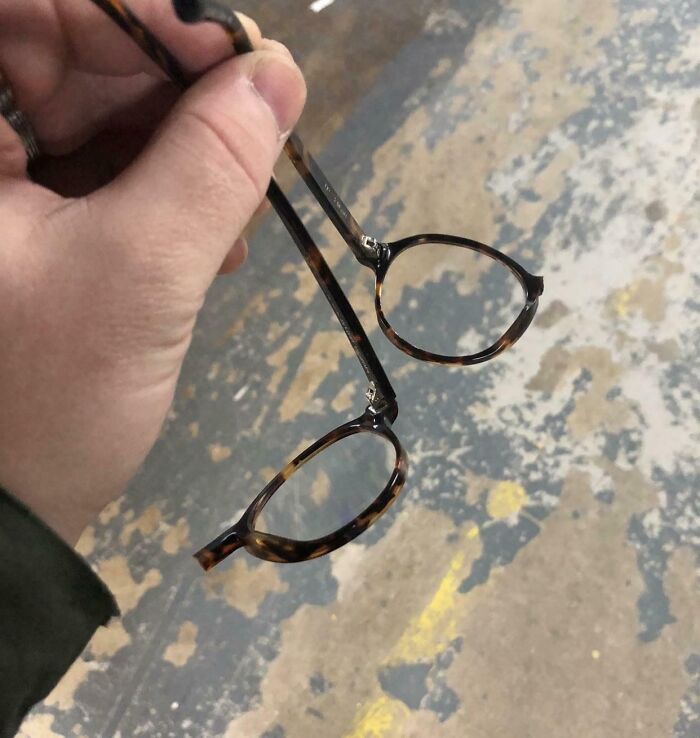 Hand holding broken glasses frame, symbolizing frustrating bosses.