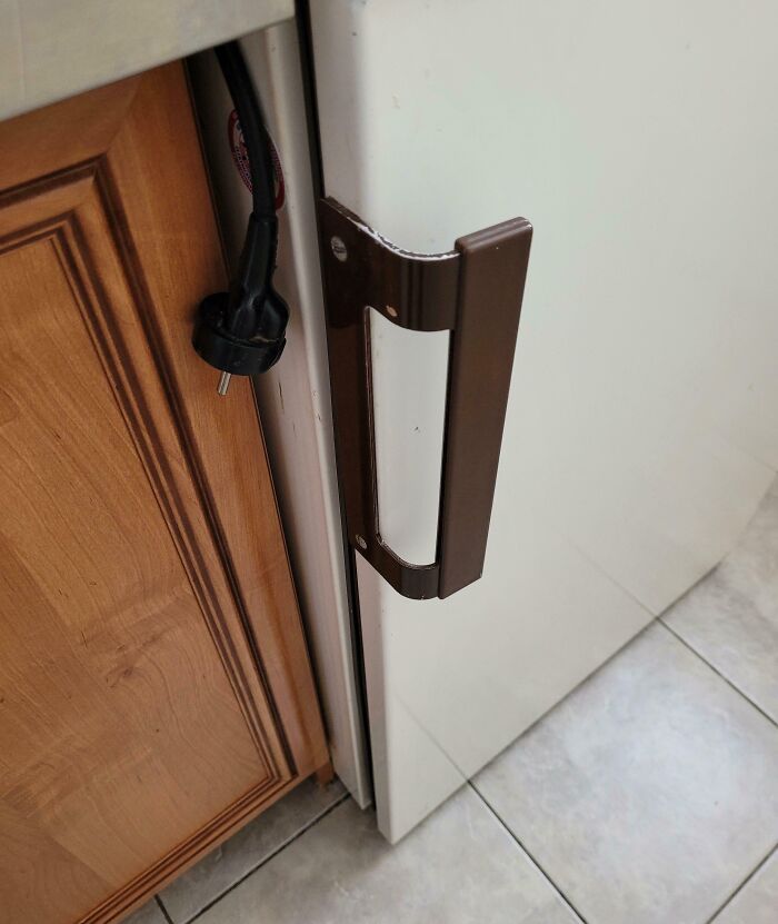 A kitchen counter with a door handle blocking an electrical socket.