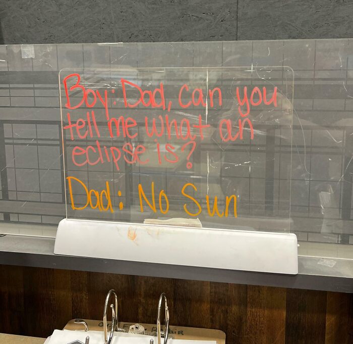 A humorous note about an eclipse written on a transparent board by a witty coworker.