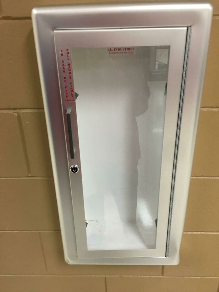 Fire extinguisher cabinet in American school hallway with handle instructions visible.