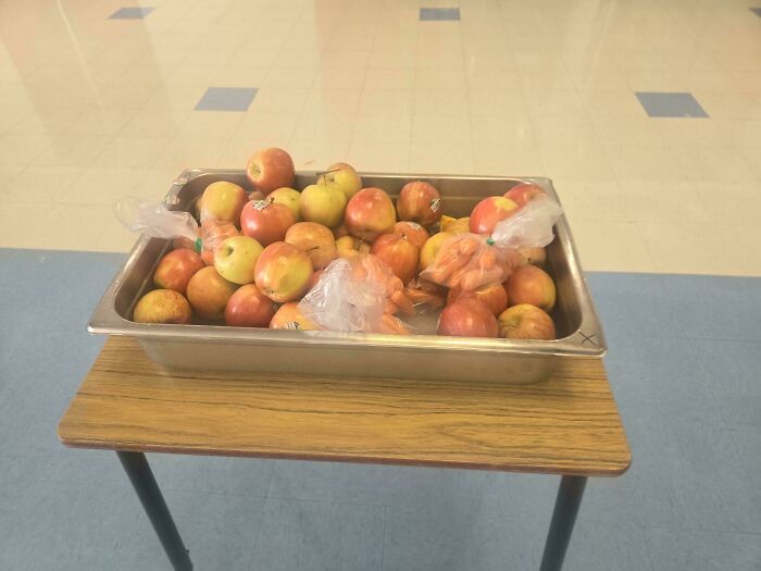 A tray of apples on a table in an American school cafeteria.