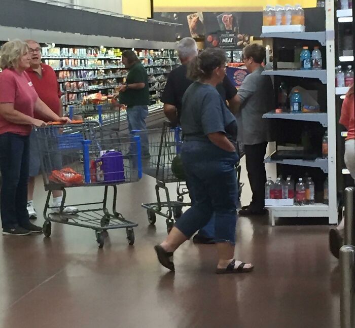 People with shopping carts blocking the aisle in a supermarket, demonstrating a lack of basic etiquette.
