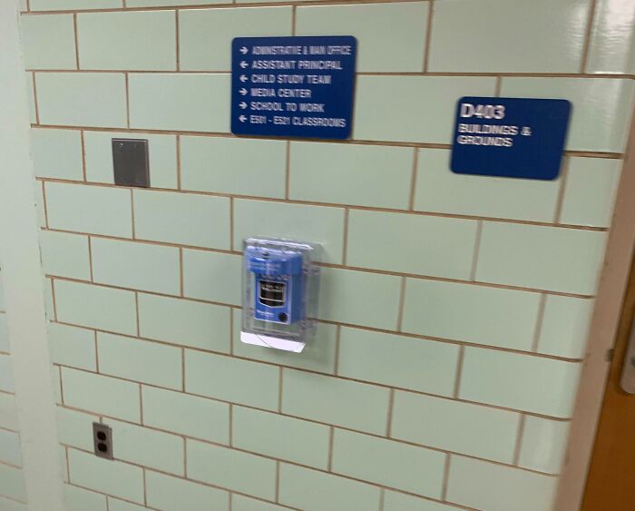 School wall with direction signs, showing layout of American educational facility, includes emergency device.