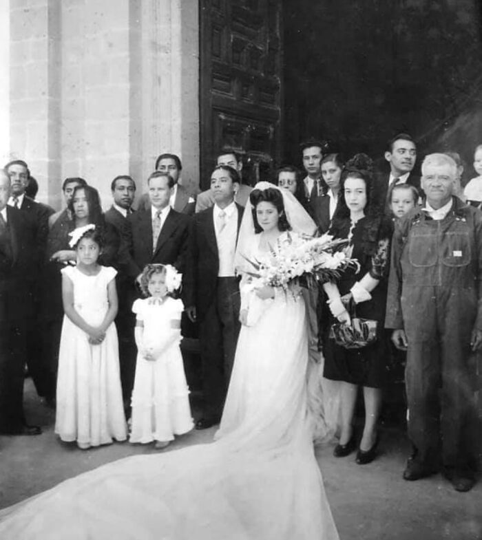 Vintage wedding photo of a bride and groom with family and friends, capturing timeless love and style.