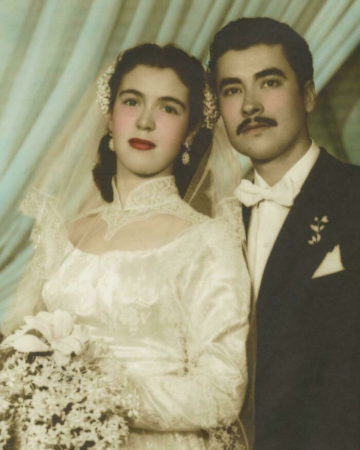 Vintage wedding photo of a couple, with the bride in a lace gown and groom in a bow tie, showcasing timeless love.