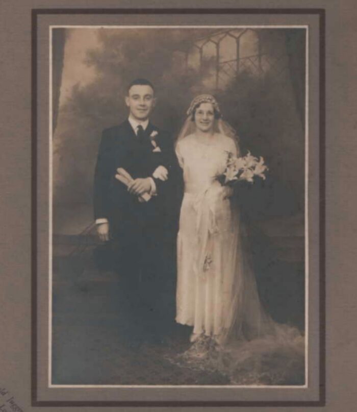 Vintage wedding photo of a couple in formal attire, the bride holding flowers, capturing timeless love.