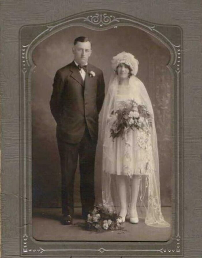Vintage wedding photo of a couple in formal attire, with the bride in a veil holding a bouquet.