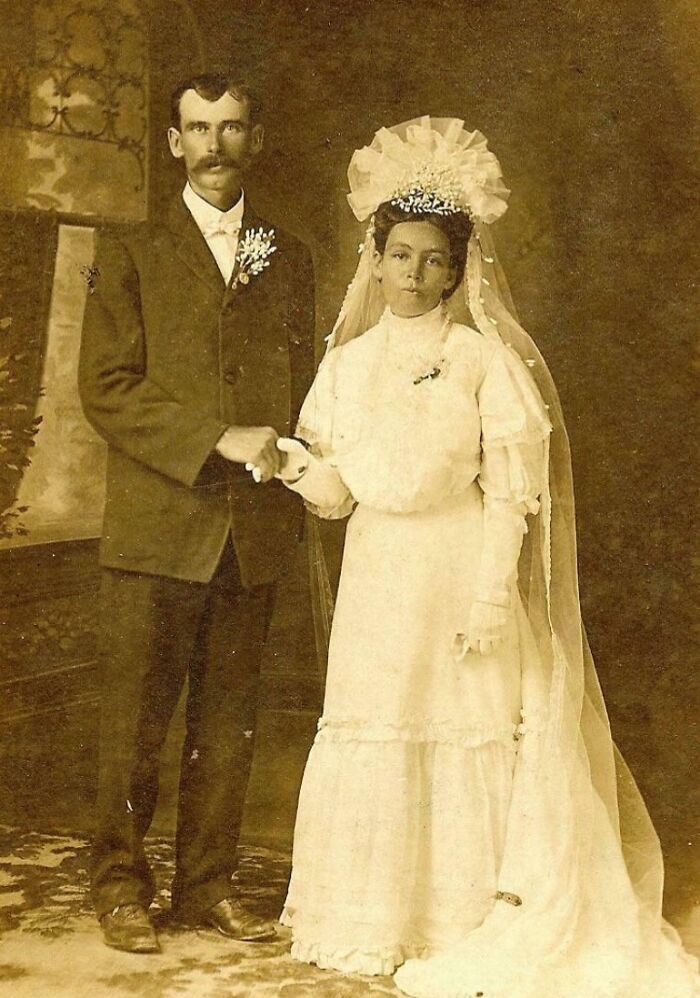 Vintage wedding photo of a bride in a long dress and groom in a suit, showcasing timeless love.