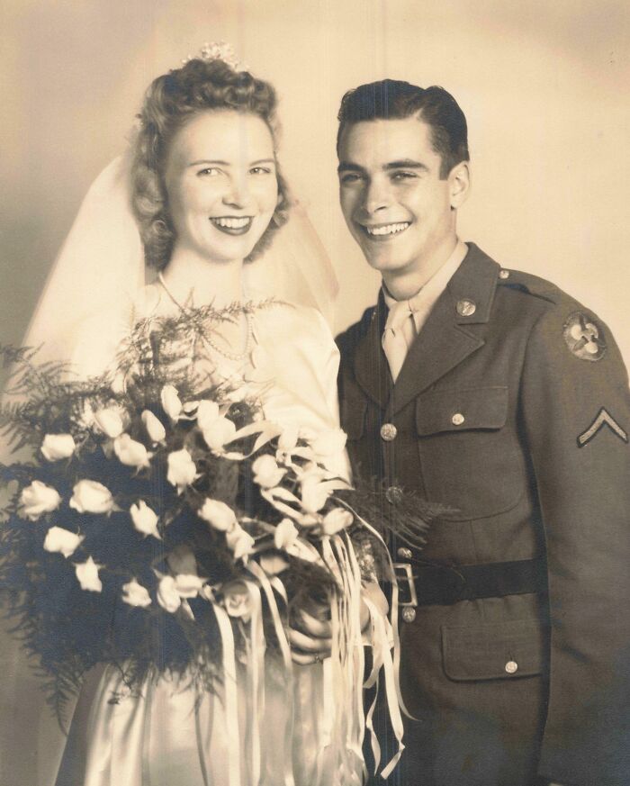 A vintage wedding couple smiles, the bride holding a bouquet, embodying timeless love and style.
