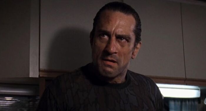 Actor portraying a difficult role with intense expression in a dimly lit room, showcasing actors going above and beyond.