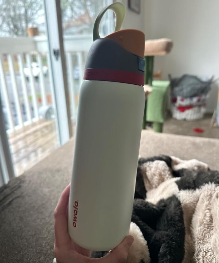 A popular Amazon bottle with colorful lid on a cozy blanket near a balcony.