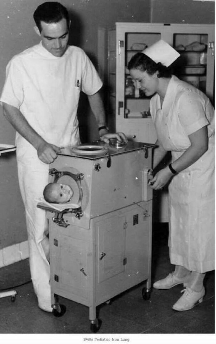 Medical staff with a baby in a 1940s iron lung, a glimpse into historical healthcare practices.