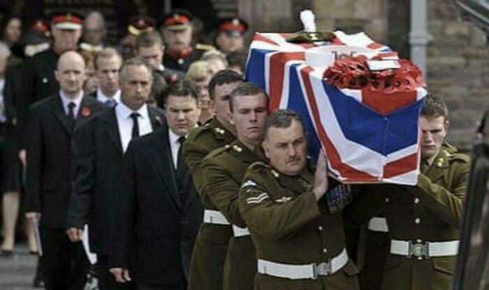 Soldiers in uniform carry a Union Jack-draped coffin during a historical military funeral procession.
