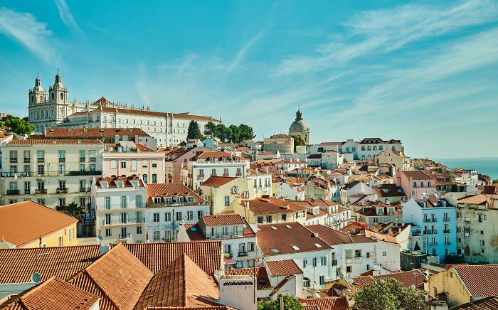 Colorful cityscape with terracotta roofs and pastel buildings under a clear blue sky, resembling a real-life painting.