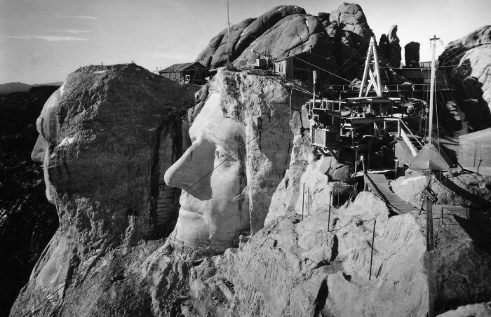 Mount Rushmore under construction, focusing on the sculpting of presidential faces, capturing a historical moment.
