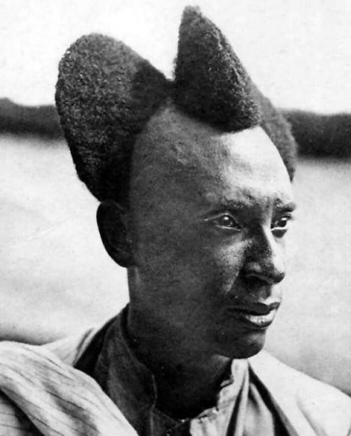Man with unique historical hairstyle, captured in black and white, showcasing cultural expression.