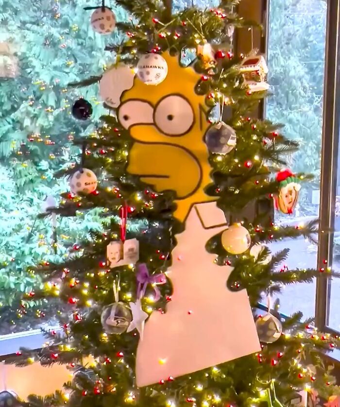 Simpsons paper cutout of Homer in a decorated Christmas tree, creating a unique real-world scene indoors.