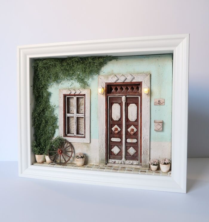 Miniature scene of a detailed door and window surrounded by greenery in a framed setting by Tamar Cohen.