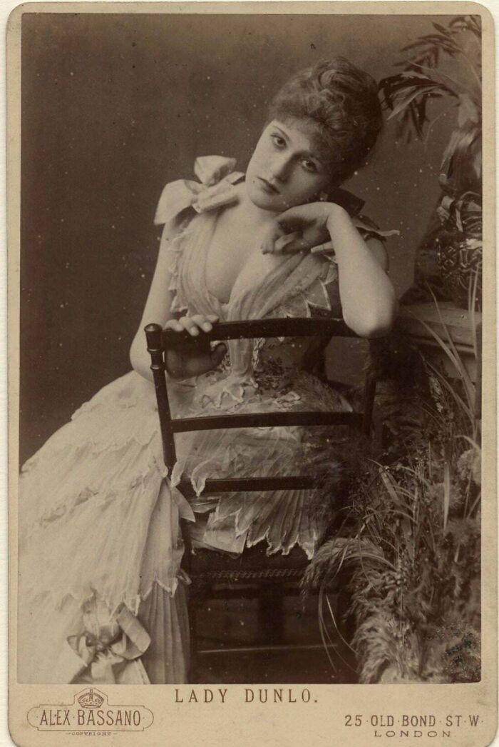 Lady in Victorian dress posing thoughtfully, historical photograph capturing a moment from the past.