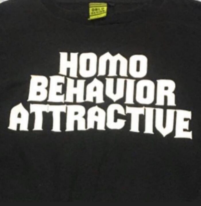 T-shirt with humorous translation: "Homo Behavior Attractive" in bold white text on black fabric.