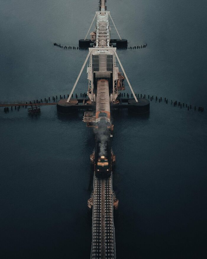 Aerial photo of a train crossing a bridge over water, showcasing the world from a unique angle.